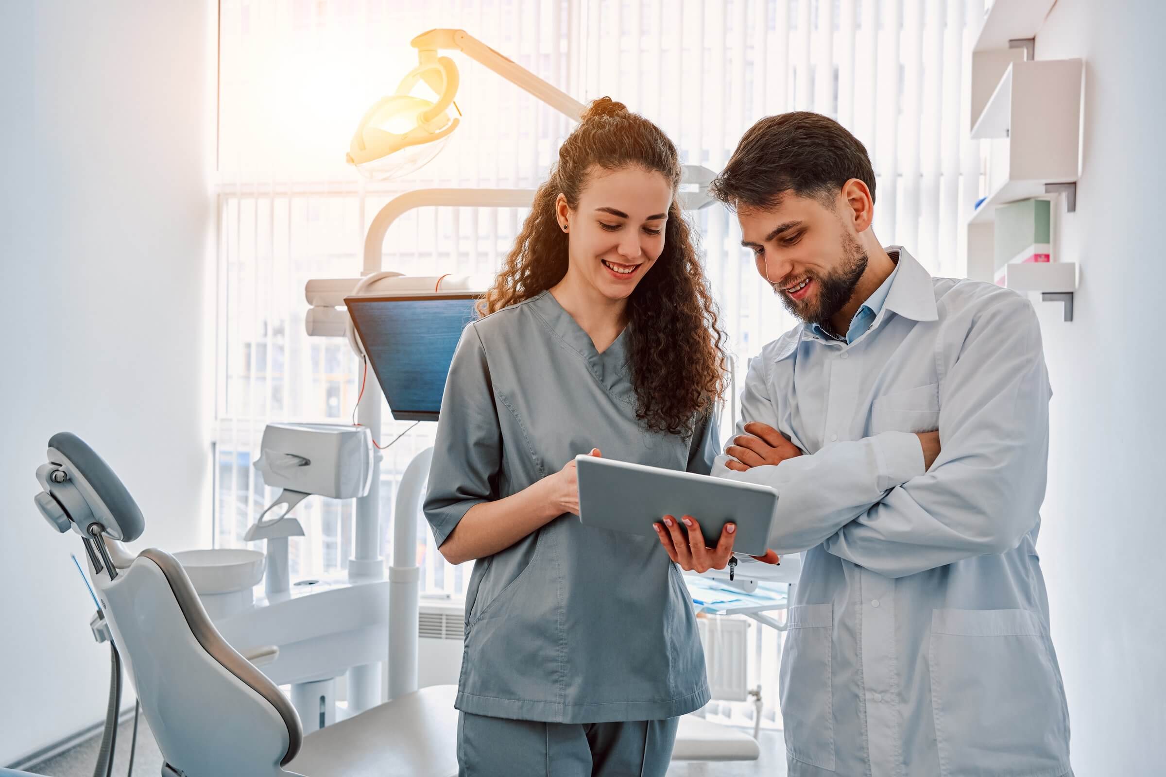 Hygienist teaching a patient proper oral care with a tablet.