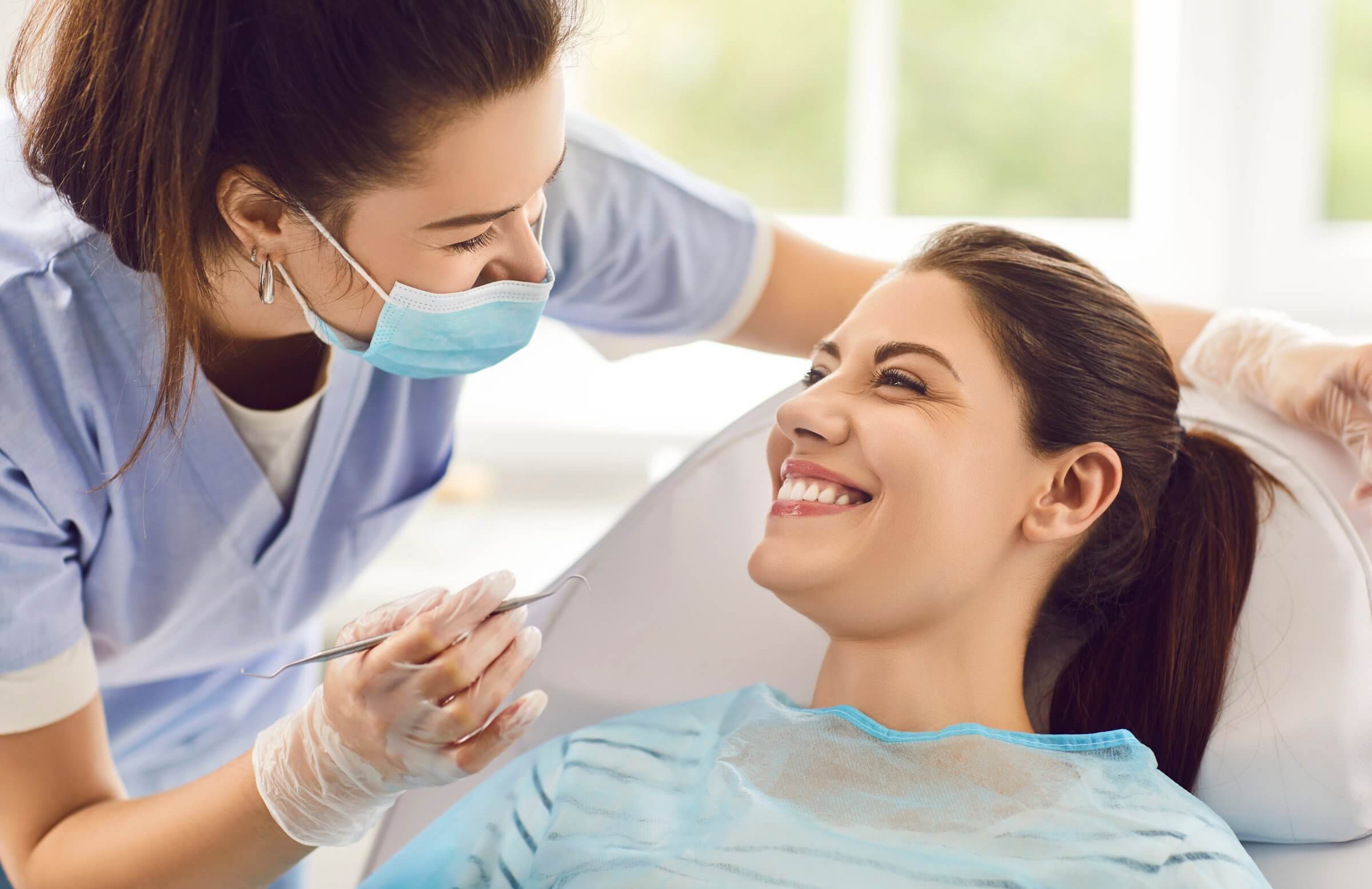 Dentist smiling at her patient after delivering a clean bill of health.