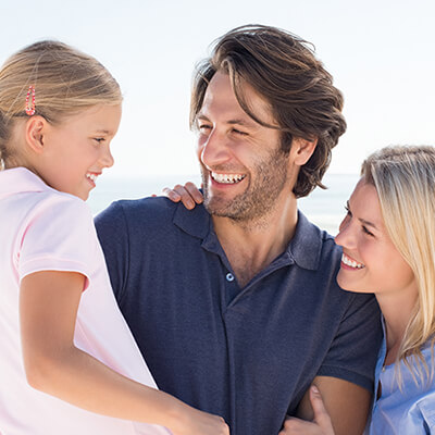 Parents smiling with daughter at the beach