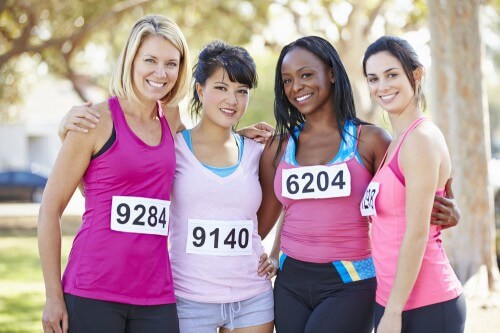 Group of lady marathon runners side hugging and smiling