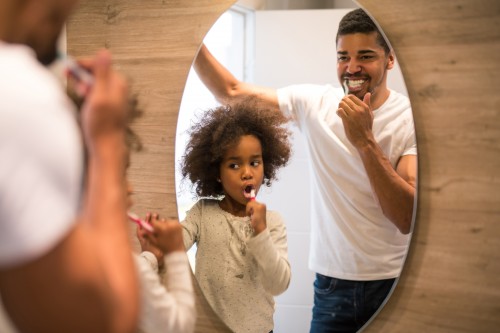father and daughter brushing teeth