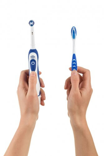 hands holding out a couple different types of electric toothbrushes