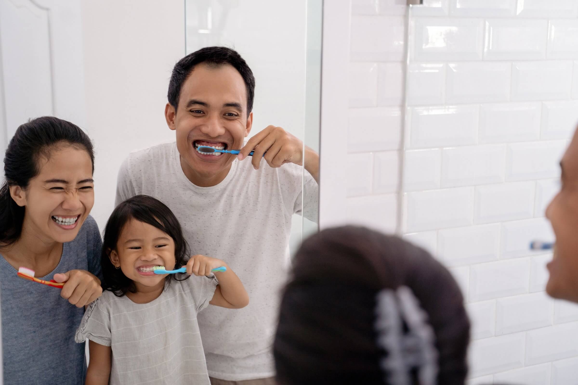 Family smiling together while brushing their teeth after trick-or-treating.